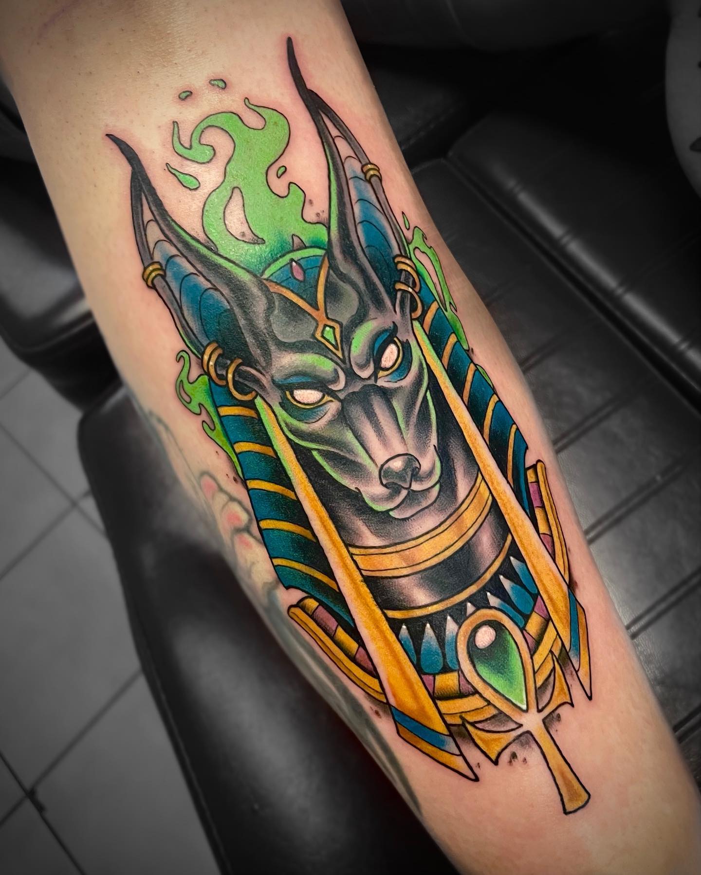Anubis tattoo with colorful inks from green to yellow.