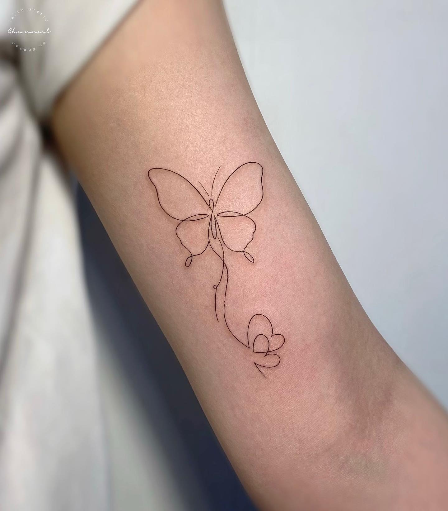 Minimalist butterfly tattoo on the bicep