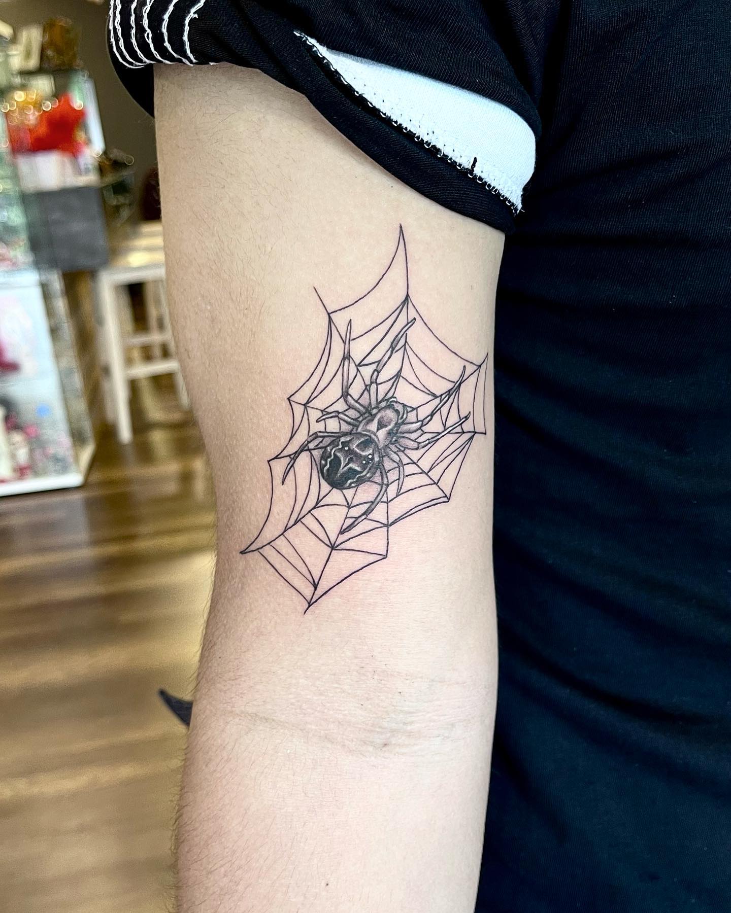 Spiders being stuck in a web will look mysterious and scary. Guys who want a tattoo that represents their biggest fears will like this all-black ink tattoo idea.