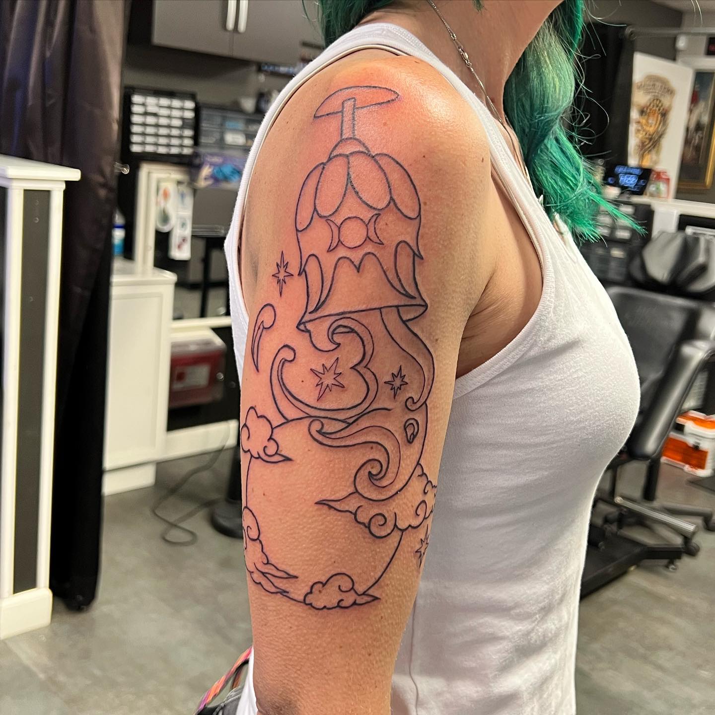 Sometimes line tattoos are a great choice for those who prefer a simple design. The moon, clouds and shiny stars form a harmony with the water that is running on them. The fun detail of glass, which bears the water, adds this nice tattoo a different look.