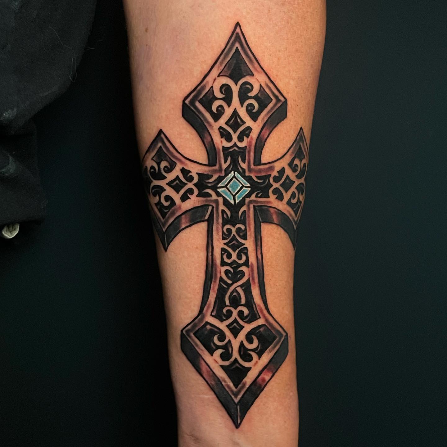 Wanna get a big cross tattoo on your arm? The cross above is full of nice motifs inside. Plus, it has a 3D effect. This effect makes it look like it has a depth. The blue sign in the middle of the cross offers an extraordinary look. You need to give it a shot. 