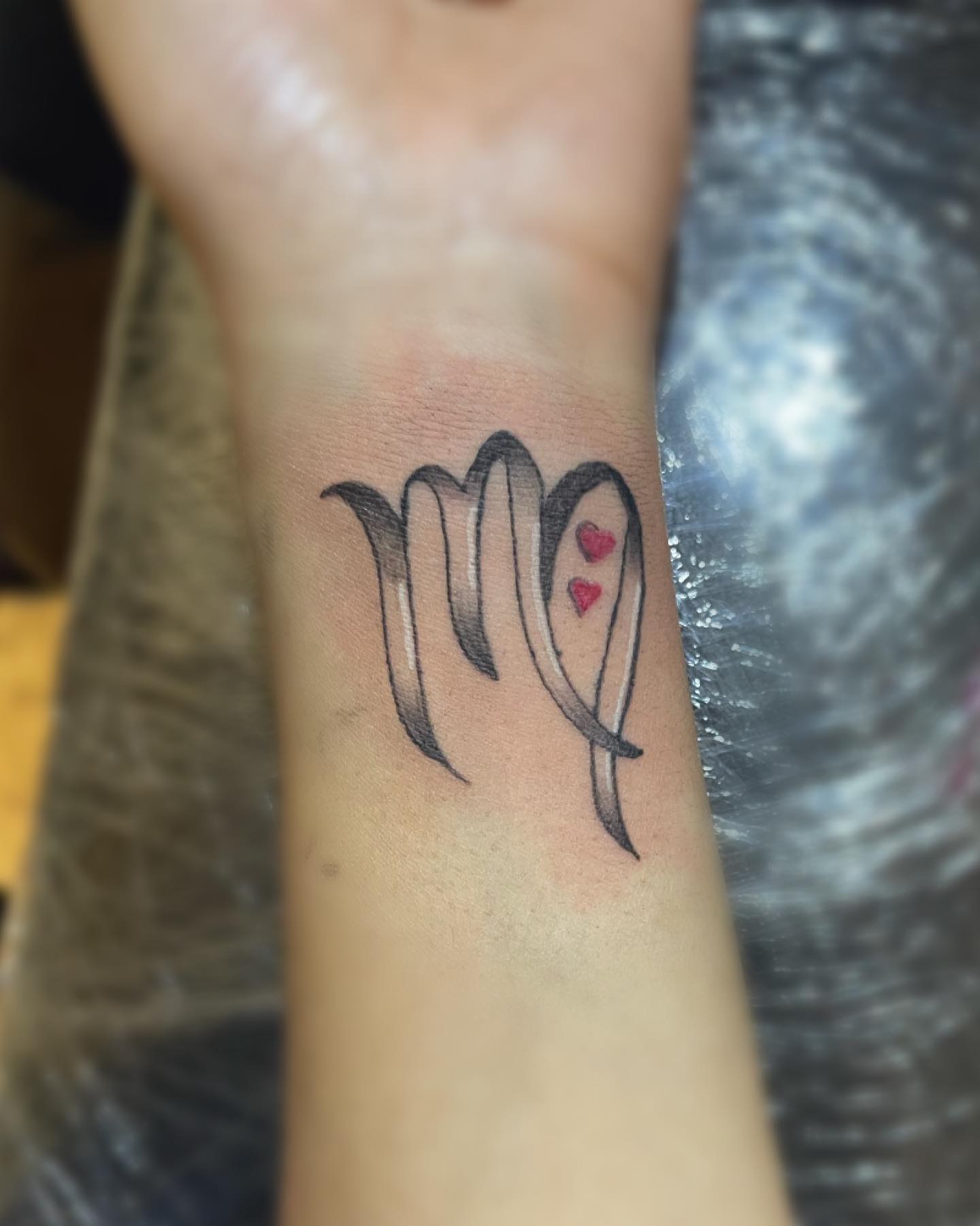 Get a Virgo tattoo on one of the most delicate locations on your body, the wrist. Adding two little red hearts can give this tattoo a cute look.