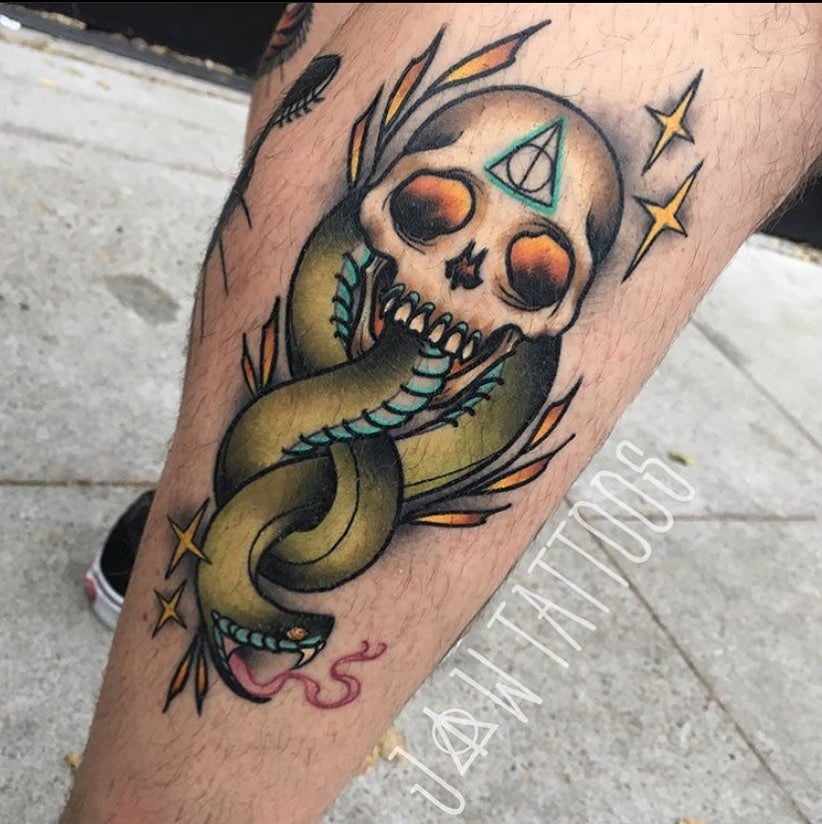 Depicting the mark of the dark lord, this death eater tattoo is ready to make your calf shine out! The dark green color of snake is quite scary and the sign of deathly hallows on the forehead of the skull is a nice detail, too.
