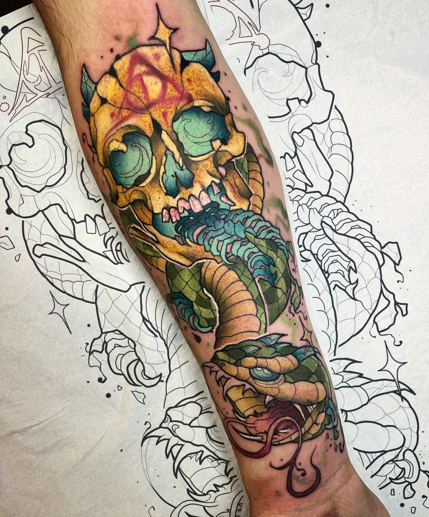 It looks like a piece of art, doesn't it? Golden, blue and green colors create a great harmony with each other and they make the tattoo look much more glamorous. Red deathly hallows sign is a nice detail on his skull's forehead, too.