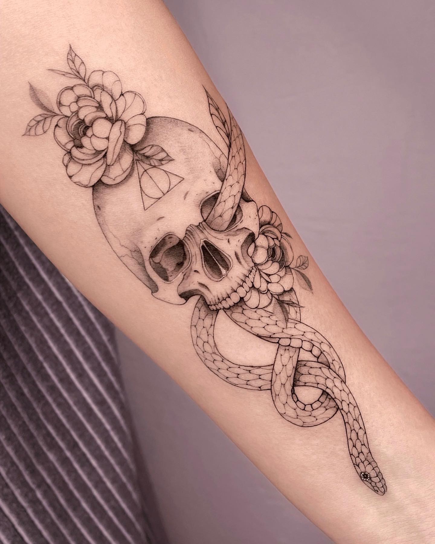 All the lines and details look so real here! Besides the great artwork, flower details give this death eater tattoo an extra beauty. Go for it if you want to stand out from the crowd.