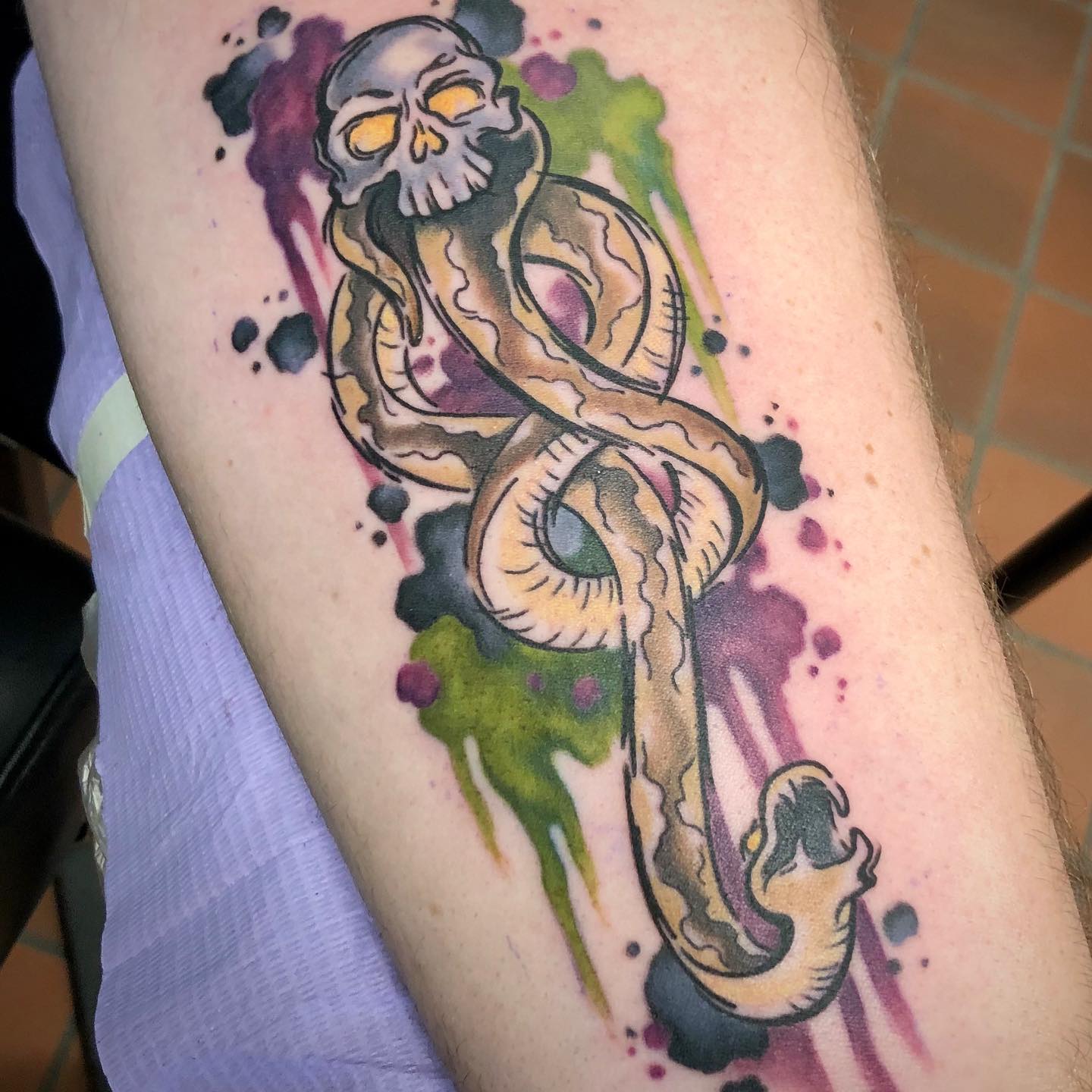 It is so hard to resist this great splash tattoo. It's so beautiful and clearly done by someone who is very talented. Soft colors of pink, green and blue shows a great harmony with the death eater sign.