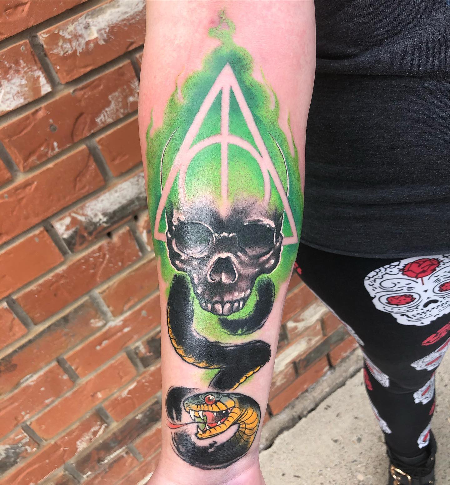 The design above differs from other ones because the highlight is deathly hallow sign behind the skull which is done in a great way. Go and get this scary tattoo.