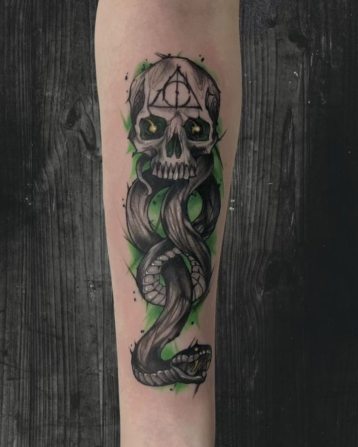 Here is an another cool death eater. The green background behind the gorgeous death eater sign adds a scarier look because of its shade. All of these shading details and effects make this tattoo fabulous.