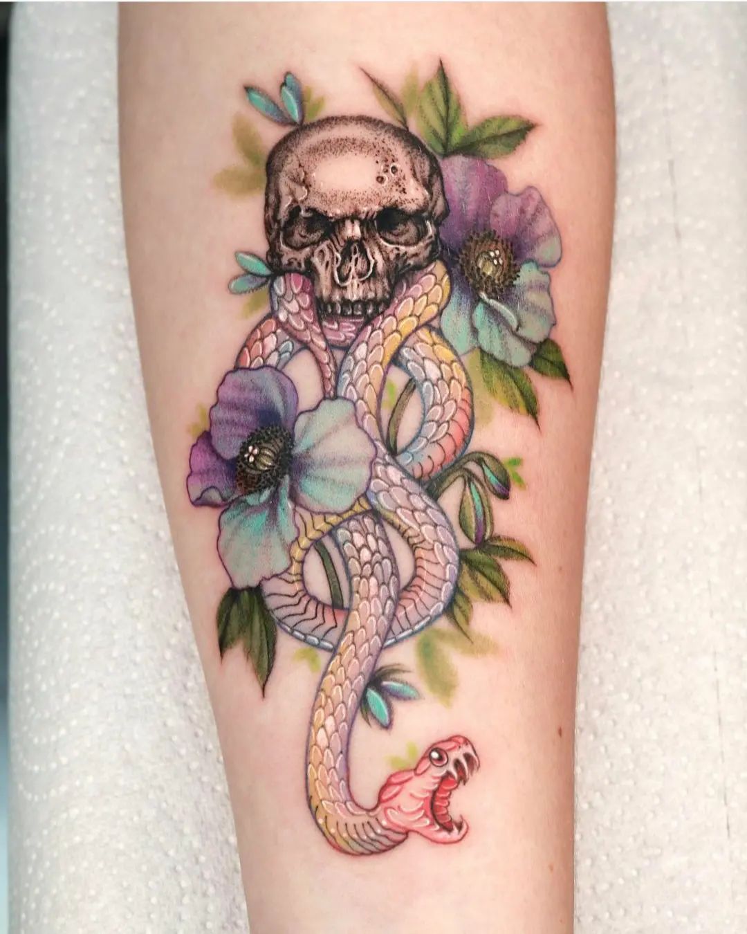 Death eater tattoo has never been this cute that much. The soft colors and flowers make a great combo with green leaves. This tattoo shows a contrast between the dark nature of death eaters with the beauty of the nature. Why don't you give it a shot?