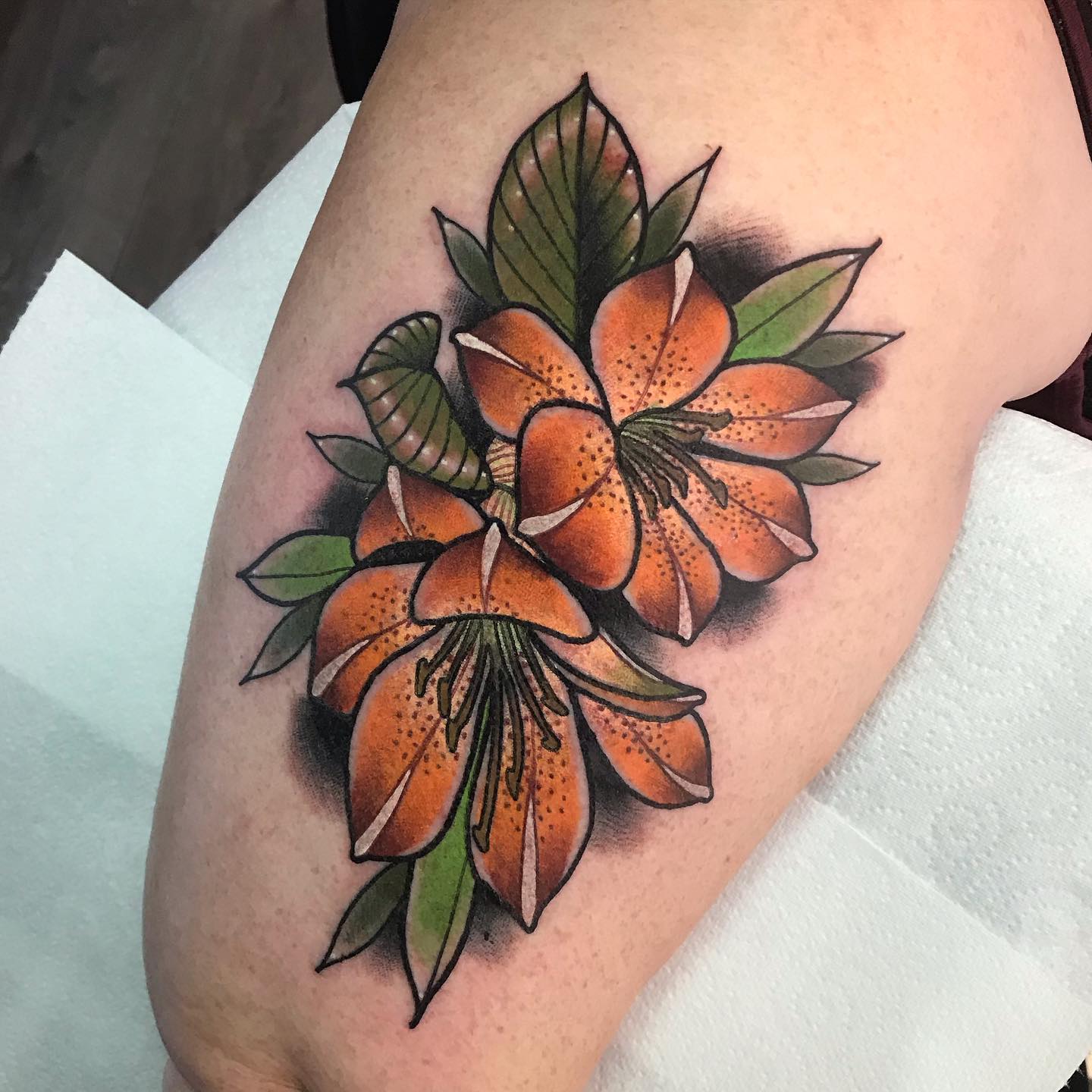 Orange lilies are a nice, soft, feminine tattoo. It's nice that the leaves are added to the design. The colors are very vibrant and they go together. Those who are looking for something pretty but not too loud and flashy will adore it for sure.