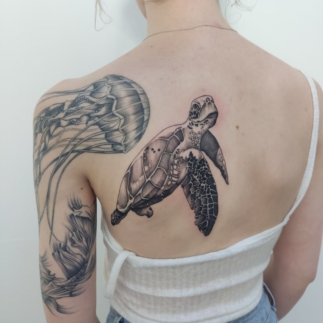 The idea of a sea turtle swimming through the ocean and being surrounded by jellyfish is appealing. This blackwork tattoo gives people a feeling of calm and peace. If you think that it is so big, keep it in mind that you won't see this tattoo every time since it is placed on your back.