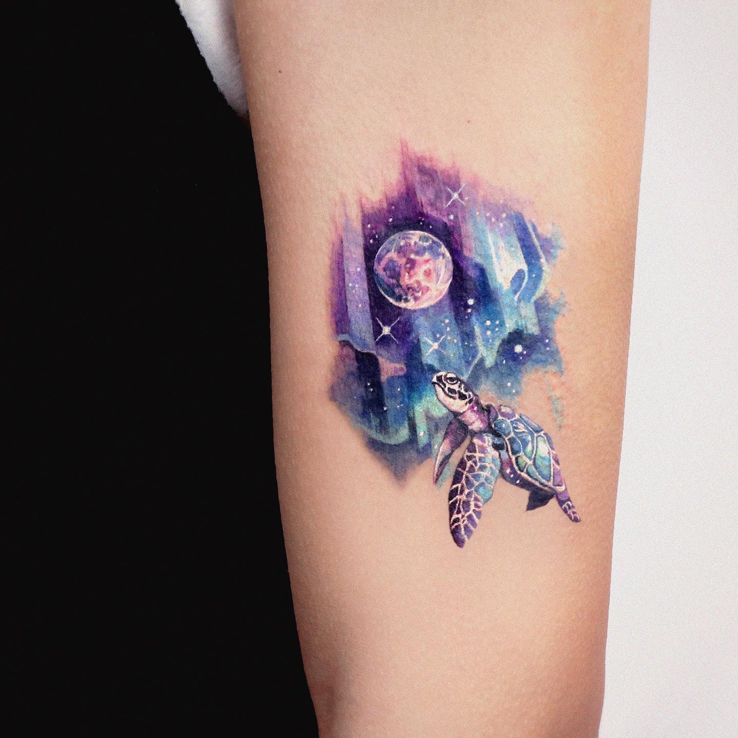 Here is another creative tattoo that looks adorable. A sea turtle and aurora are a great combo with purple and blue color palette. The sea turtle is rising above to the aurora. The whole look is amazing with these two beautiful things in life, isn't it?