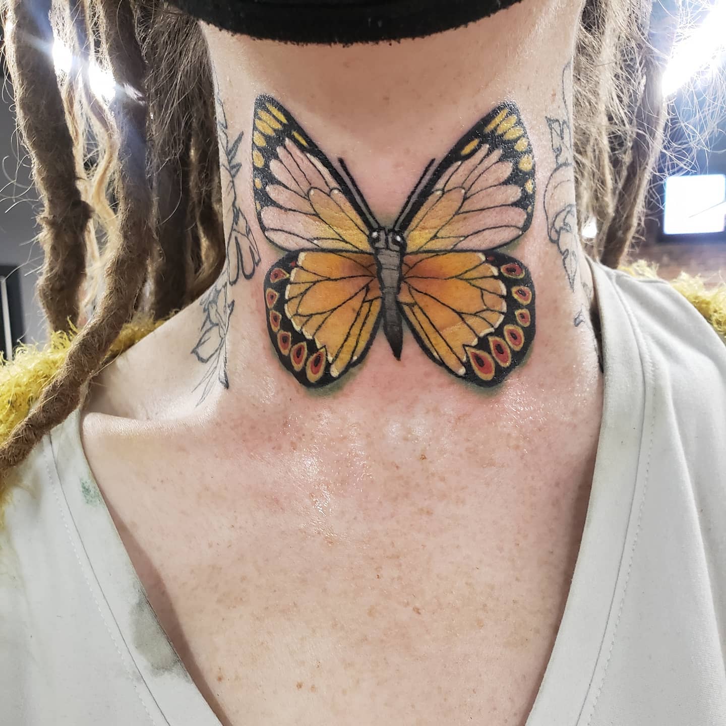Woman receiving butterfly tattoo at her neck stock photo