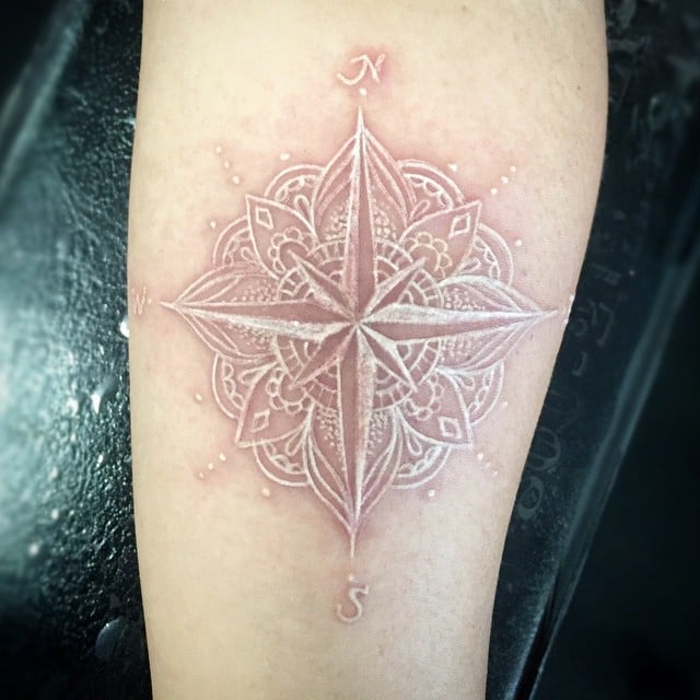 Here is a white ink lotus compass tattoo on arm! It's such a unique and beautiful way to express your love for travel. It's really cool that you're able to show off your travels with such an intricate design.