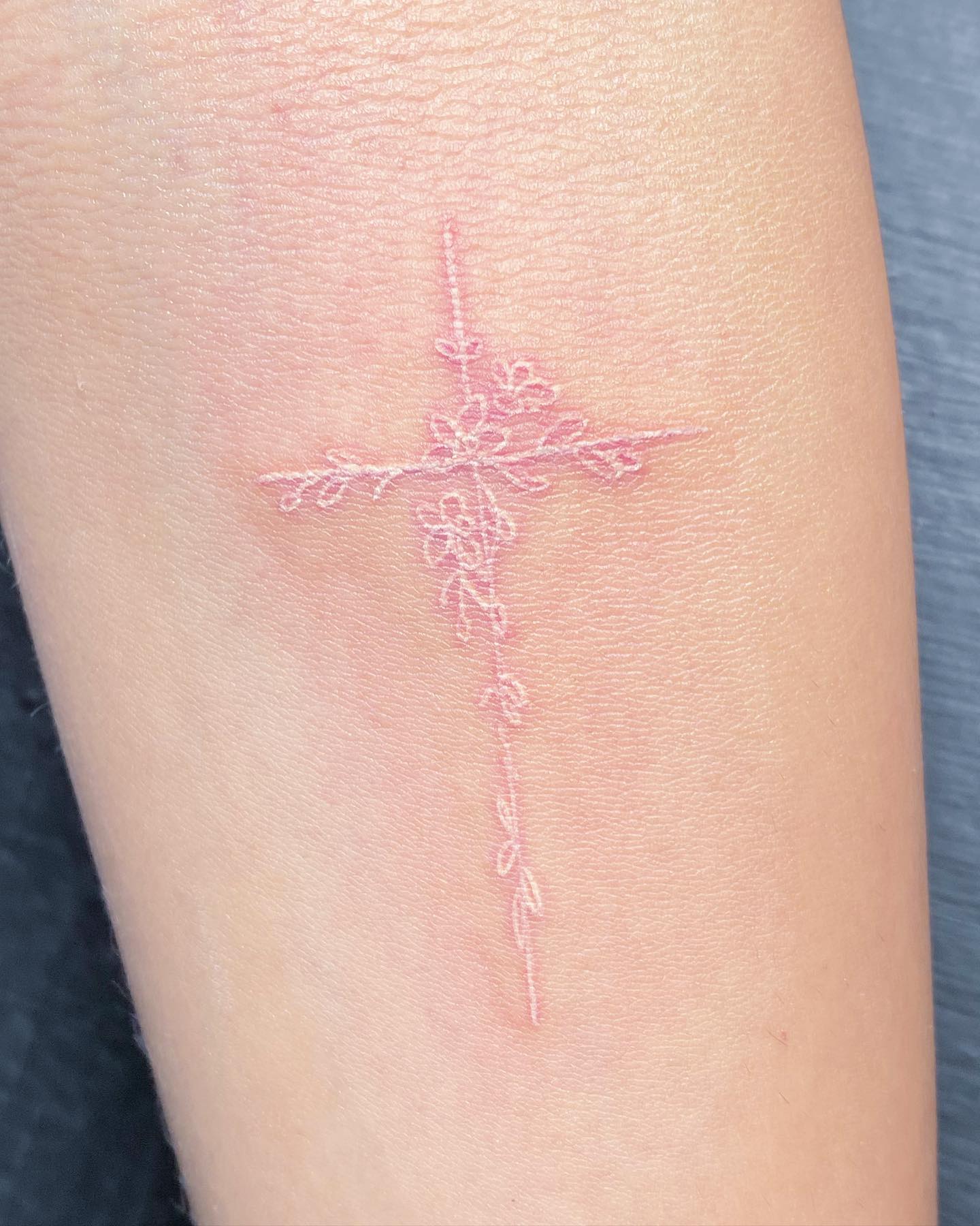 Cross tattoos are a great way to express your faith. It's a reminder that you are not alone in this world and that God is with you. Plus, white ink will symbolize your pure love.