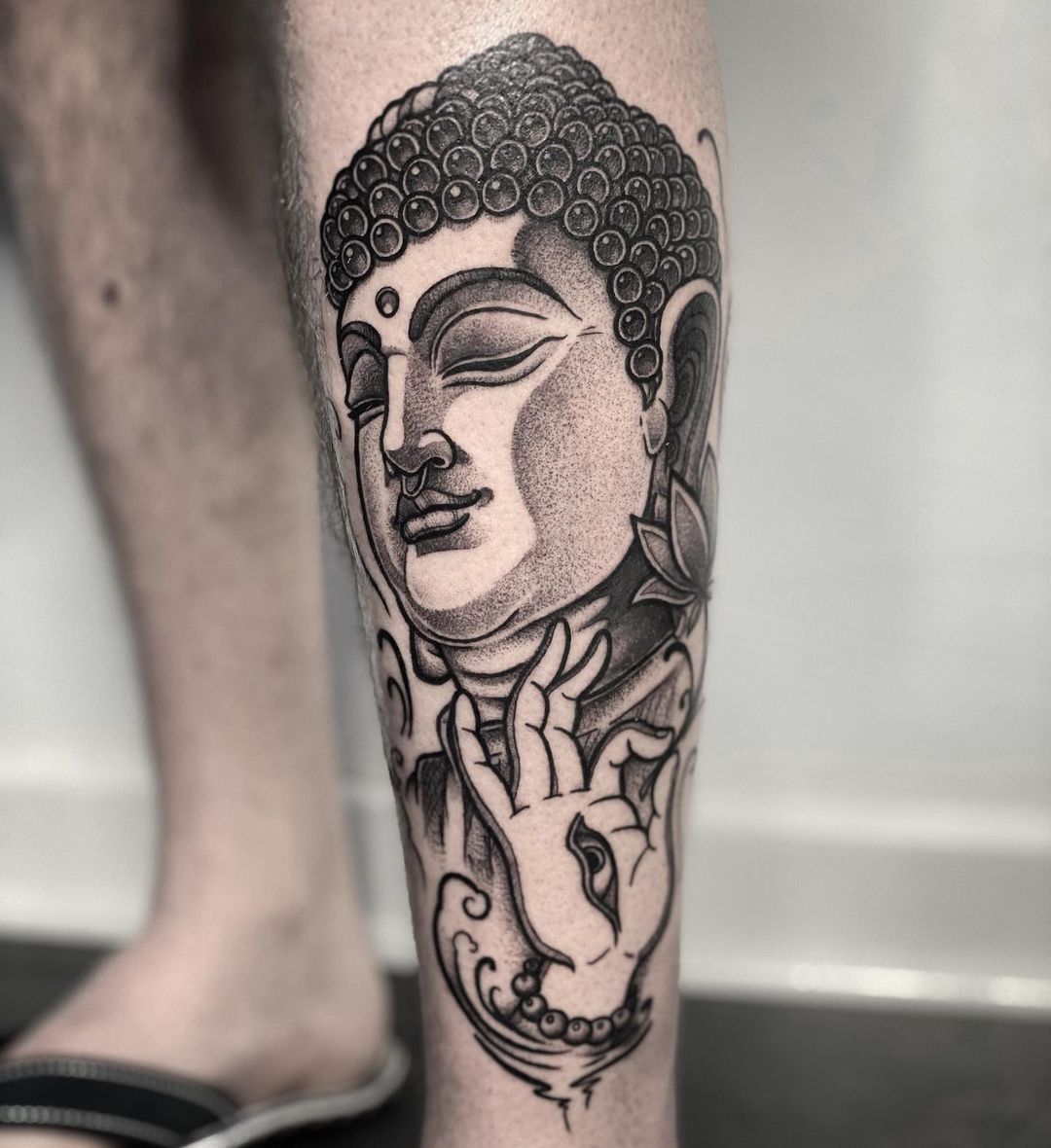 Black and grey Buddha tattoo on the upper arm
